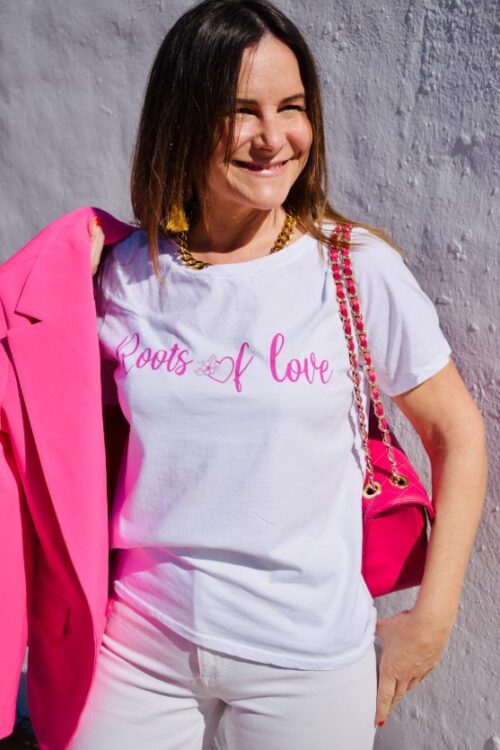 Mujer vistiendo camiseta blanca con letras en rosa fucsia en el pecho.