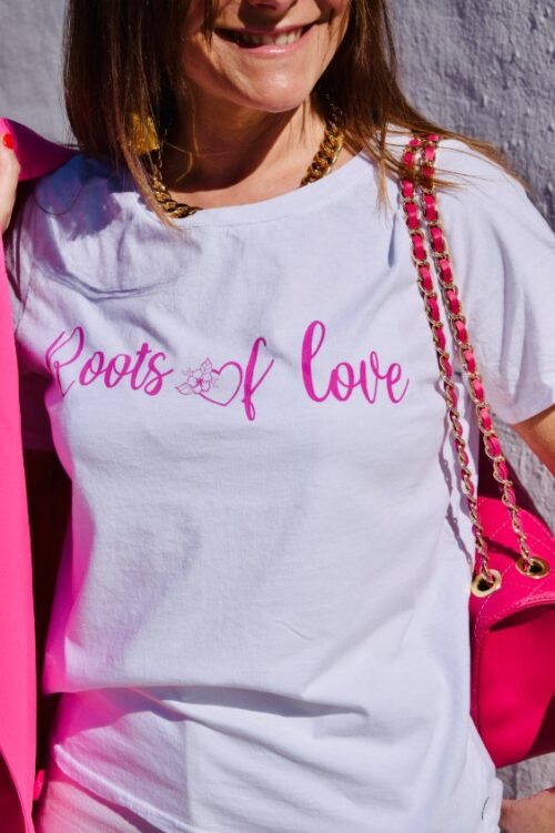 Mujer con camiseta de manga corta blanca con letras rosas en el pecho.