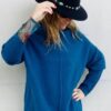 Mujer con jersey de cuello vuelto de color azul petroleo y sombrero Boho negro.