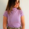 Mujer vistiendo jersey lila de cuello alto y manga corta