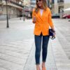 Mujer vistiendo blazer naranja y pantalón vaquero