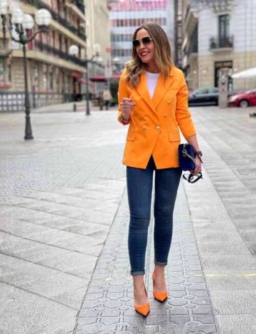 Mujer vistiendo blazer naranja y pantalón vaquero
