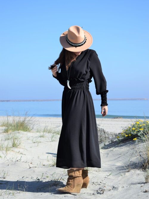 Mujer vistiendo vestido negro largo y sombrero beige.