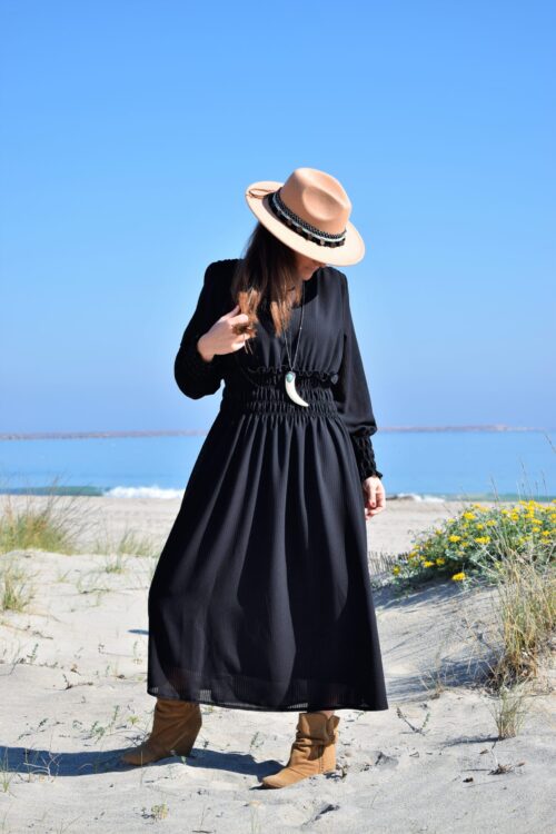 Mujer llevando vestido negro y sombrero beige.