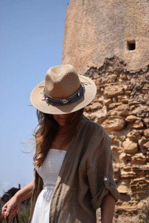 Mujer vistiendo Sombrero de mujer beige estilo Boho con ala ancho con faro de fondo
