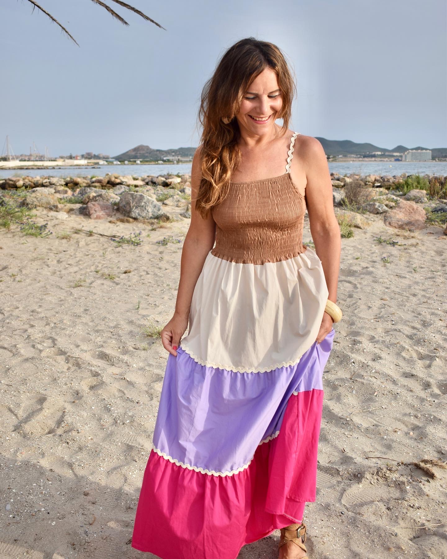 Mujer em la playa llevando vestido largo multicolor.