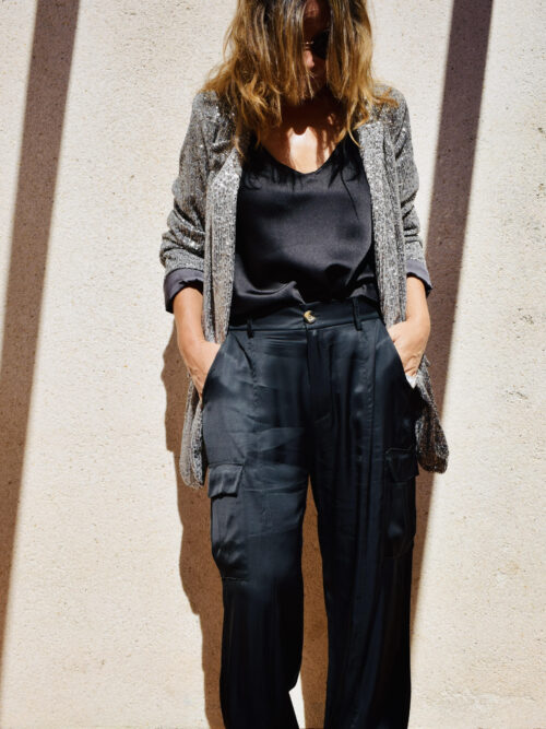 Mujer vistiendo pantalon cargo negro con blazer gris de lentejuelas.