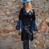 Mujer luciendi vestido estilo Boho de terciopelo negro con bordados en tonos azules.