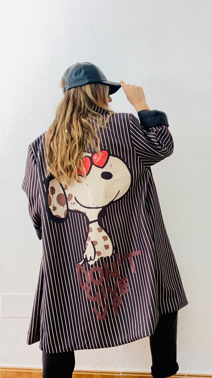 Mujer vistiendo abrigo oversize negro con espalda decorada con Snoopy